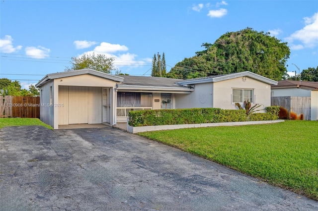 ranch-style house with aphalt driveway, a front lawn, and fence