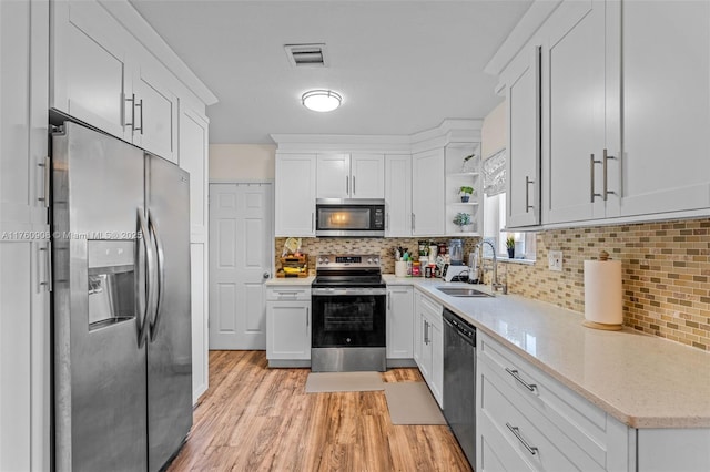 kitchen featuring visible vents, light wood-type flooring, a sink, open shelves, and appliances with stainless steel finishes