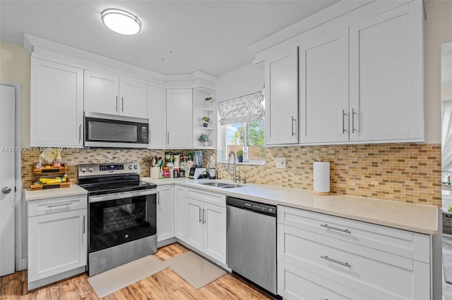 kitchen featuring a sink, stainless steel appliances, open shelves, and white cabinetry