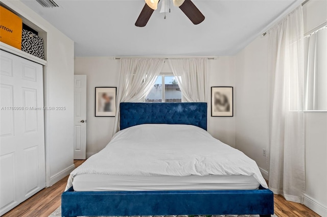 bedroom featuring ceiling fan, visible vents, baseboards, and wood finished floors