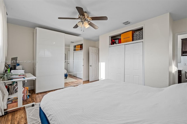 bedroom featuring a closet, visible vents, ensuite bath, and wood finished floors