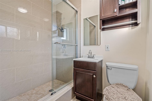 bathroom featuring a shower stall, toilet, and vanity