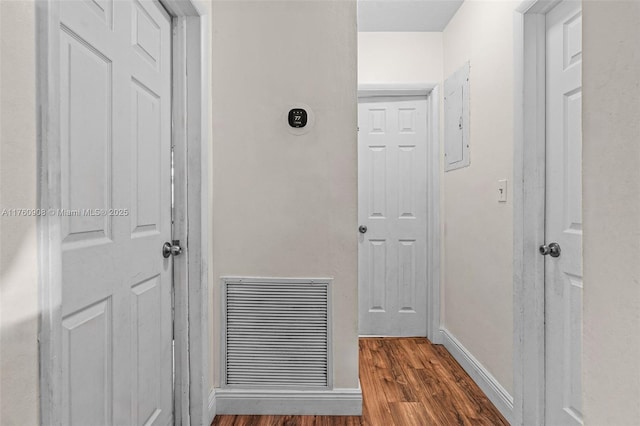 corridor with electric panel, visible vents, baseboards, and wood finished floors