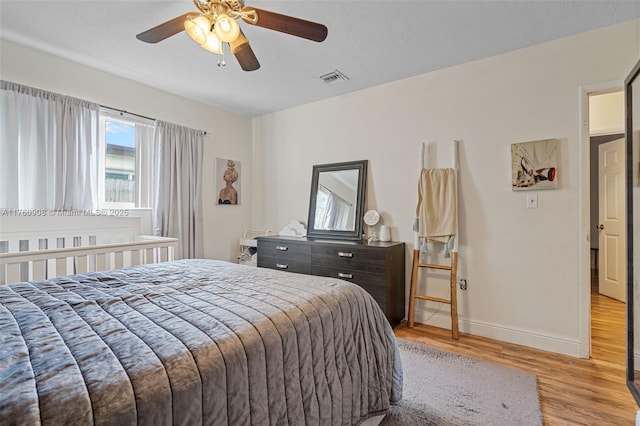 bedroom featuring a ceiling fan, baseboards, visible vents, and light wood-type flooring