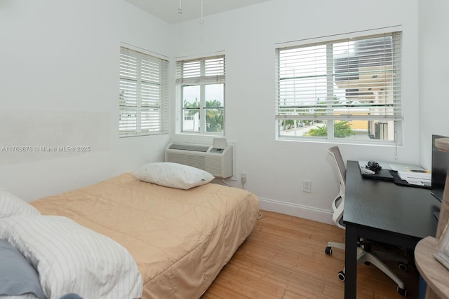 bedroom with baseboards, multiple windows, and light wood finished floors