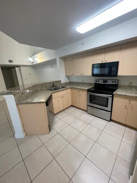 kitchen with a peninsula, light tile patterned floors, appliances with stainless steel finishes, and a sink