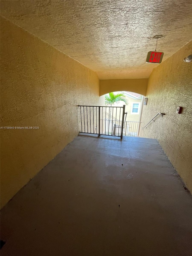 empty room with a textured ceiling, concrete flooring, and a textured wall