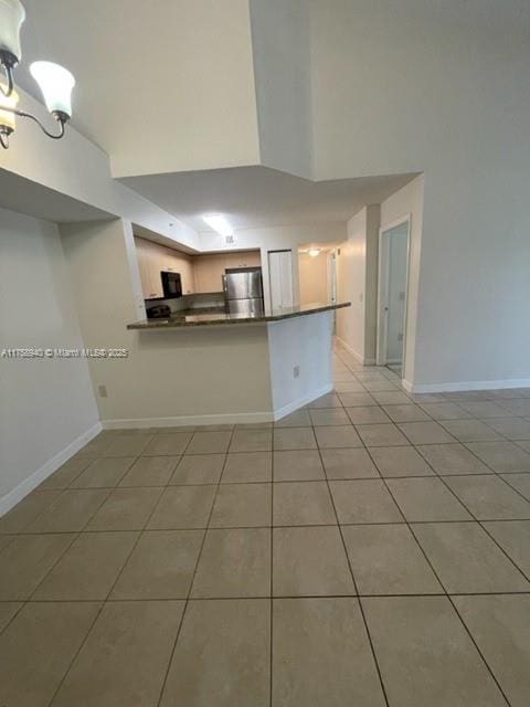 kitchen featuring baseboards, stainless steel fridge, dark countertops, and tile patterned flooring