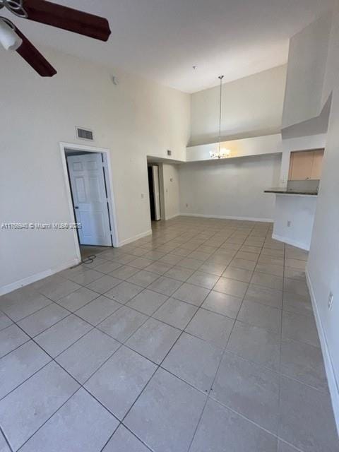 unfurnished room featuring tile patterned flooring, ceiling fan with notable chandelier, visible vents, and high vaulted ceiling