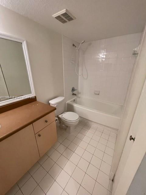 bathroom featuring visible vents, toilet, vanity, tile patterned floors, and washtub / shower combination