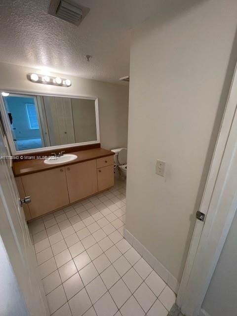 bathroom featuring tile patterned floors, visible vents, toilet, a textured ceiling, and vanity