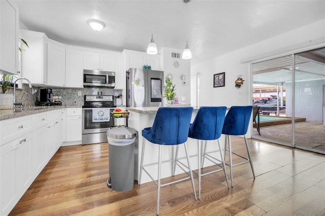 kitchen featuring tasteful backsplash, visible vents, a center island, a kitchen bar, and stainless steel appliances