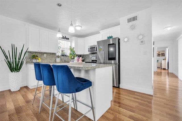 kitchen with light wood-style floors, visible vents, backsplash, and appliances with stainless steel finishes