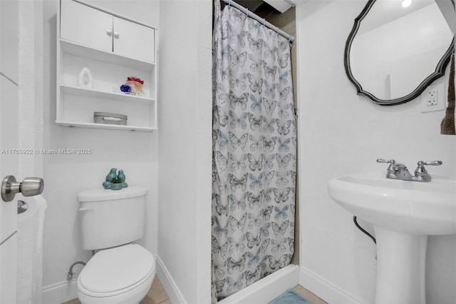 bathroom with curtained shower, toilet, baseboards, and a sink