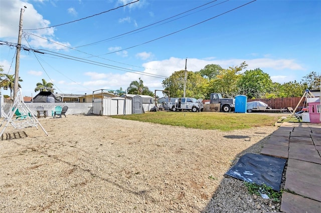 view of yard featuring an outbuilding, a shed, and fence