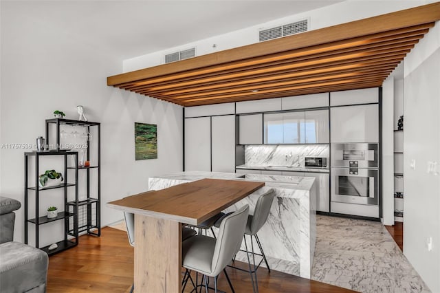 kitchen featuring dark wood-style flooring, a breakfast bar area, visible vents, and stainless steel oven