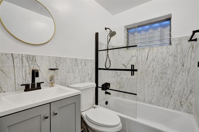 full bathroom with a wainscoted wall, toilet, vanity, tile walls, and  shower combination