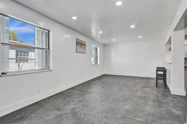 spare room featuring recessed lighting, baseboards, and concrete floors