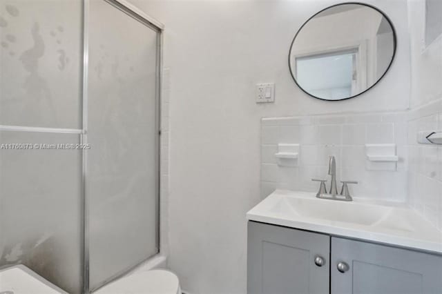 bathroom featuring vanity, toilet, tasteful backsplash, and a stall shower