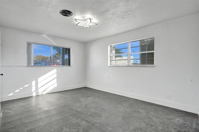 unfurnished room with visible vents, a textured ceiling, concrete flooring, and baseboards