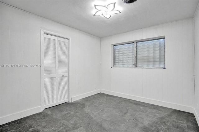 unfurnished bedroom featuring baseboards, a closet, and concrete floors