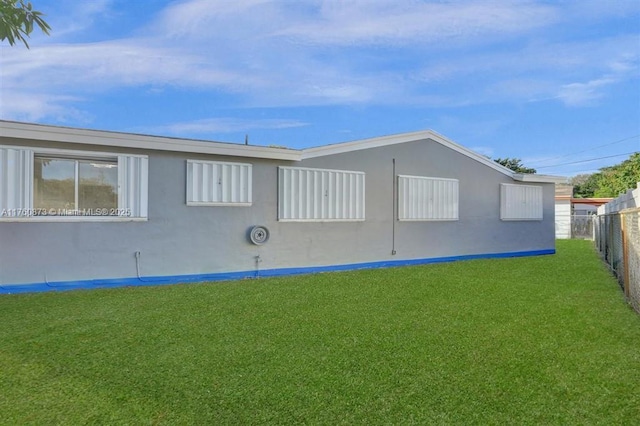 rear view of property featuring a lawn and fence