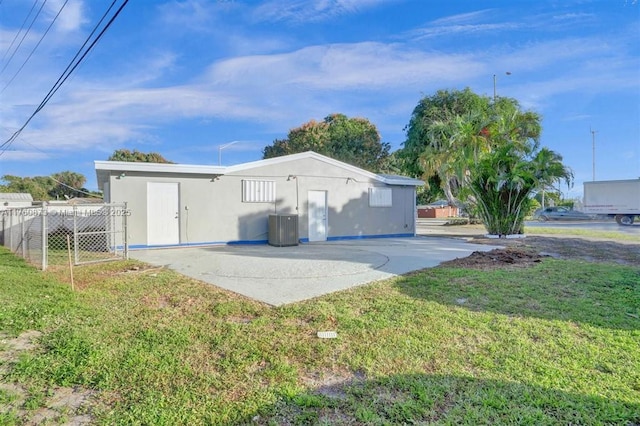 back of property with a patio, a lawn, and central AC