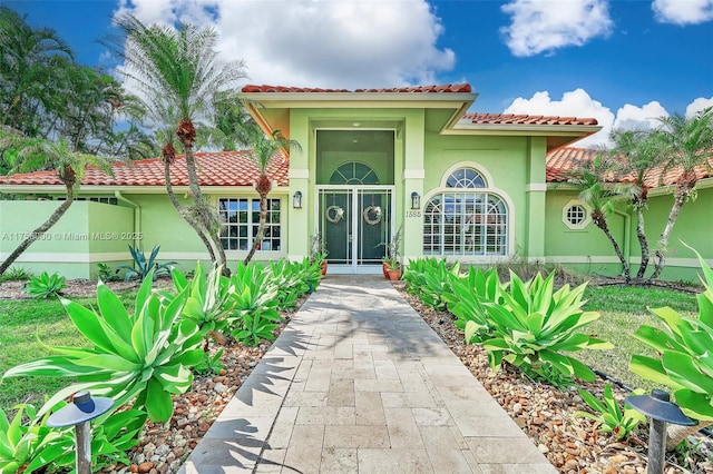 view of exterior entry with stucco siding and a tile roof