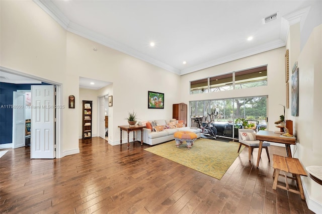 living area featuring visible vents, wood-type flooring, a high ceiling, and crown molding