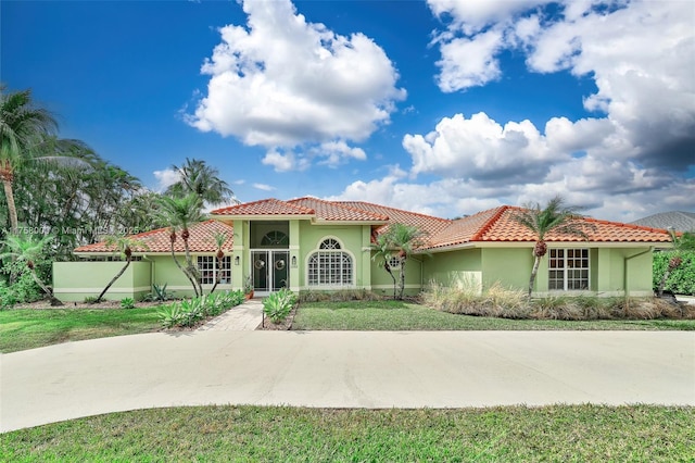 mediterranean / spanish house featuring a tile roof and stucco siding