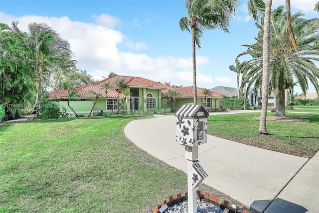 view of front of home with stucco siding, a tiled roof, concrete driveway, and a front yard