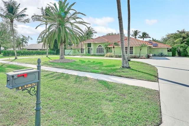 mediterranean / spanish-style house featuring a front lawn, a tile roof, driveway, and stucco siding