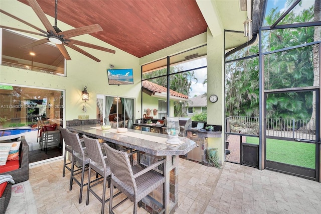 sunroom with ceiling fan, wooden ceiling, and lofted ceiling