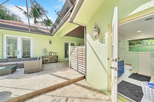 view of patio with glass enclosure, french doors, visible vents, and an outdoor hangout area