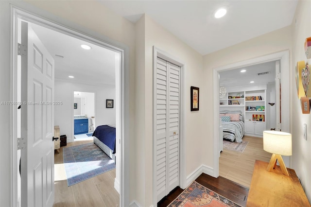 hall featuring visible vents, baseboards, built in features, recessed lighting, and wood finished floors