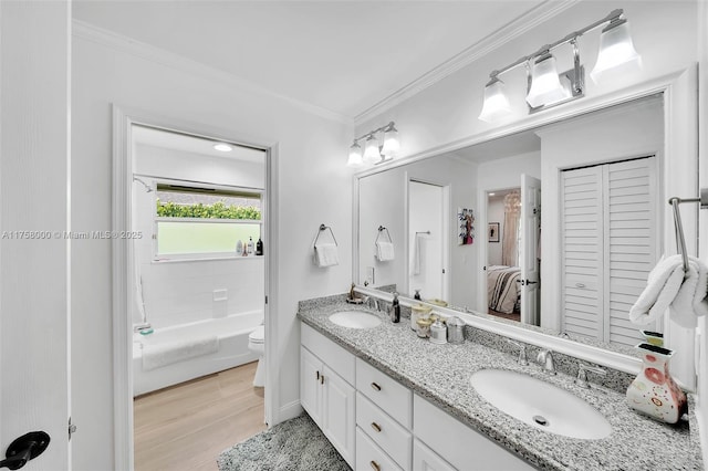 full bathroom with toilet, ornamental molding, wood finished floors, and a sink