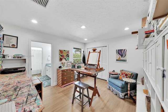 office area featuring recessed lighting, visible vents, light wood-type flooring, and a textured ceiling