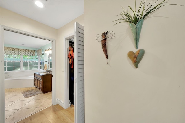 corridor with light wood finished floors and a sink