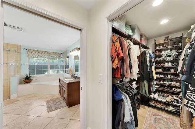 spacious closet with light tile patterned floors, visible vents, and a sink