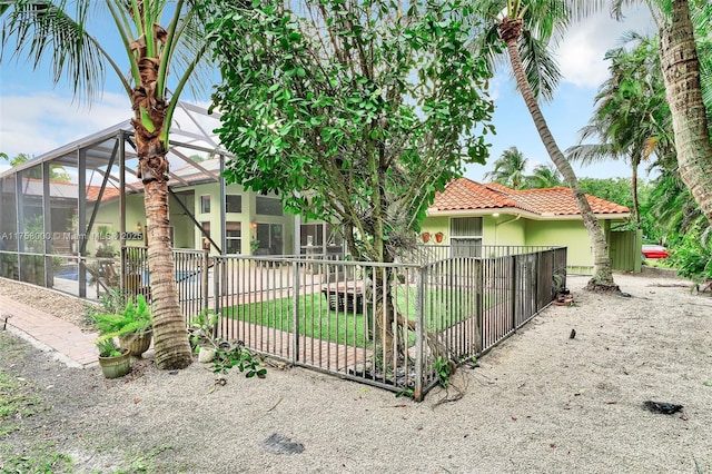 exterior space featuring a gate, fence, stucco siding, a lanai, and a tiled roof