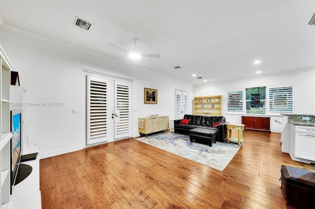 living area featuring recessed lighting, visible vents, light wood finished floors, and ornamental molding