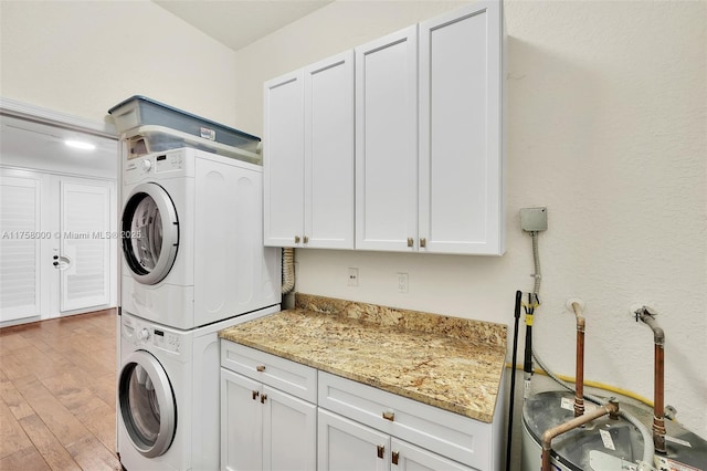 washroom with light wood-style flooring, cabinet space, and stacked washer and clothes dryer