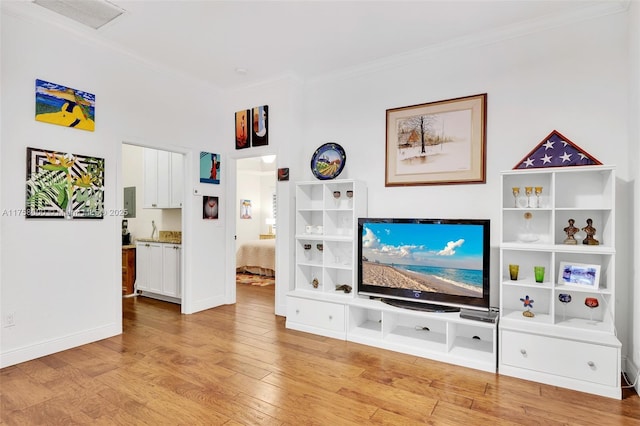 living room with baseboards, ornamental molding, and light wood finished floors