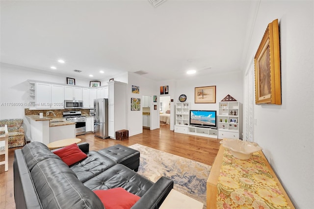 living area with recessed lighting, light wood-type flooring, visible vents, and crown molding