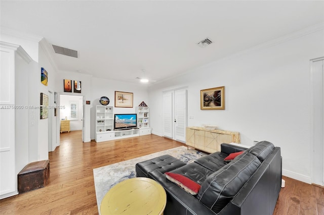 living room with crown molding, visible vents, and light wood-type flooring