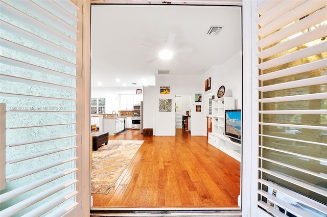 interior space with a sink, light wood-style floors, visible vents, and ornamental molding