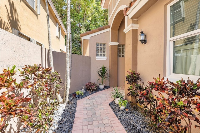 view of exterior entry featuring stucco siding and fence