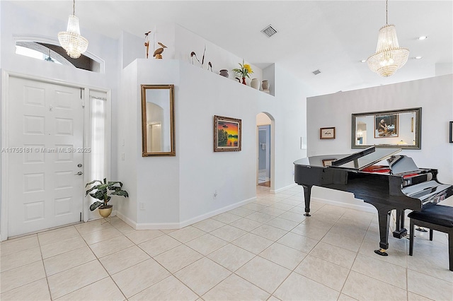 foyer entrance with visible vents, high vaulted ceiling, arched walkways, light tile patterned flooring, and baseboards