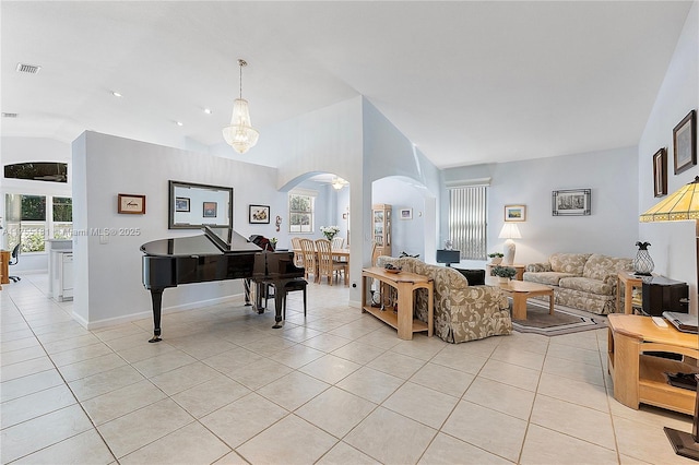 living area featuring light tile patterned floors, visible vents, a healthy amount of sunlight, and vaulted ceiling