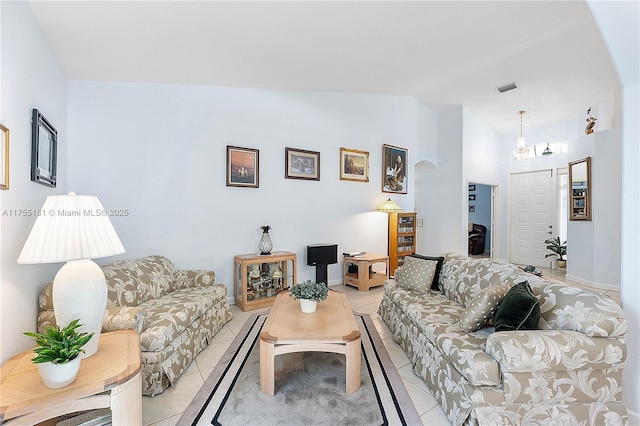 living area featuring light tile patterned floors, visible vents, lofted ceiling, and baseboards